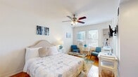 Located in Chicago's prestigious Gold Coast neighborhood, this thoughtfully designed studio at 1100 N La Salle Drive maximizes every square foot of its compact footprint. The open-plan main area seamlessly integrates the sleeping, living, and dining zones, creating a versatile and functional layout. Warm parquet hardwood flooring runs throughout, lending a classic, timeless character to the space.

The sleeping area accommodates a full-sized bed and features a ceiling fan with integrated lighting, a built-in closet, and decorative wall art that adds a pop of color. Natural light pours in through multiple windows, offering views of the surrounding Chicago skyline. A cozy seating nook with two mid-century modern blue chairs and a small side table creates a distinct lounge area near the windows.

The kitchen is efficiently equipped with gray upper cabinetry, stainless steel appliances including a gas range, dishwasher, and an in-unit washer, as well as a compact sink and countertop workspace. A small dining table positioned nearby completes the functional layout.

The bathroom is bright and clean, featuring a window for natural light, a toilet, and a sink with an adjacent mirror, maintaining the space's crisp white aesthetic throughout. This studio offers a practical and stylish urban living solution in one of Chicago's most desirable neighborhoods.