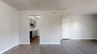 This single-floor residence offers a clean, functional layout designed for comfortable everyday living. The open living area is finished with rich, dark hardwood-style flooring and neutral gray walls, creating a versatile backdrop for any décor. A sliding glass door with vertical blinds connects the living space to an outdoor area, allowing natural light to filter in. A dedicated storage closet is conveniently located within the living area.

The galley-style kitchen is thoughtfully outfitted with gray cabinetry, light quartz-style countertops, a mosaic tile backsplash, a stainless steel sink, and white appliances including a coil-top range and refrigerator. The dark flooring continues seamlessly throughout the kitchen, adding a cohesive feel.

The bedrooms are carpeted in a warm beige tone and each features ceiling fans with lighting. Windows bring in natural light and outdoor views, enhancing the sense of openness in each room.

Two bathrooms serve the unit. The full bathroom includes a tiled shower-tub combination and dark hardwood-style flooring. The second bathroom features a gray vanity with a white countertop, a medicine cabinet mirror, and matching flooring. Both bathrooms maintain a clean, minimalist aesthetic consistent with the rest of the space.