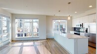 Located at 3883 S Moody Ave in Portland, Oregon, this modern single-floor residence offers a thoughtfully designed open-concept layout filled with natural light. The living area features warm hardwood-style flooring and expansive windows with glass patio doors that open to a private balcony, framing sweeping views of the surrounding Portland cityscape and beyond.

The contemporary kitchen is a standout feature, centered around a generous quartz-topped island with an undermount sink and pendant lighting overhead. White flat-front cabinetry extends to the ceiling for ample storage, while stainless steel appliances — including a refrigerator, range, and microwave — and a navy blue tile backsplash add a refined, modern touch. A corner window bathes the kitchen in additional natural light.

The bedroom is carpeted and well-proportioned, featuring a large window with city views and access to a spacious walk-in closet outfitted with wire shelving on multiple walls for generous storage.

Two bathrooms serve the residence. The primary bathroom includes dark wood cabinetry, a white quartz vanity, hardwood-style flooring, a soaking tub, and direct access to the walk-in closet. The secondary bathroom mirrors this refined aesthetic with a tub-shower combination, dark cabinetry, and clean white finishes throughout.