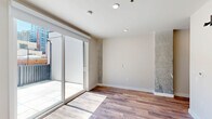 Located at 1314 Spring Garden St in Philadelphia, PA, this thoughtfully designed unit offers a compact yet efficient single-floor layout that maximizes every square foot. The interior opens through a hallway lined with a streamlined galley kitchenette, featuring crisp white cabinetry, open shelving, a black cooktop, and stainless steel appliances — all set against clean white walls and warm wood-tone flooring that runs throughout the space.

The main living area is bright and airy, bathed in natural light streaming through large sliding glass doors that open directly onto a private outdoor patio. Exposed concrete accent walls add an industrial character that contrasts beautifully with the modern finishes. A sleek barn door adds a stylish, space-saving touch to the room's design.

The bathroom is finished to a high standard, featuring large-format light tile flooring, a wall-mounted toilet, a floating vanity with a deep rectangular basin sink, and a walk-in shower — all in a clean, contemporary palette.

The outdoor patio is a standout feature, offering generous tiled space enclosed by modern metal railings with views of Philadelphia's surrounding urban architecture, including charming historic brick buildings. This unit combines modern urban living with thoughtful design details throughout.