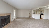 Located at 5575 Rosebriar Way in Orlando, FL, this single-floor, 2-bedroom, 2-bathroom home offers a comfortable and functional layout. The spacious living room is a standout feature, showcasing a tile-surround wood-burning fireplace, soft carpet flooring, a textured ceiling, and access to a private exterior door flanked by windows that fill the room with natural light. The open layout connects seamlessly to the kitchen via a pass-through counter, making the combined living and dining area feel airy and connected. The galley-style kitchen features hardwood-style flooring, white cabinetry, open shelving, stainless steel refrigerator, a gas range, and a dishwasher, along with a closet for additional storage. Both bathrooms are finished with hardwood-style flooring, white vanity cabinetry, large mirrors, and tiled shower-tub combinations. The two bedrooms are carpeted and well-lit by windows with blinds, each equipped with a ceiling fan. The primary bedroom offers a generous footprint, while the second bedroom provides comfortable accommodations. A hallway connects the private areas of the home. The overall ambiance is neutral and move-in ready, with a clean, consistent palette throughout.