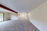 Located at 404 Deerfield Rd in East Syracuse, NY, this two-bedroom, one-bathroom residence offers a well-organized single-floor layout designed for comfortable everyday living. The combined living and dining area forms the heart of the home, featuring plush wall-to-wall carpeting, a distinctive exposed wood ceiling beam, and a ceiling fan. A sliding glass door floods the space with natural light and opens directly onto a private balcony with a railed enclosure, offering views of a landscaped lawn and surrounding neighborhood. The kitchen is efficiently laid out with warm wood cabinetry, light countertops, tile flooring, and a full suite of white appliances including a gas range, dishwasher, and refrigerator. A window above the sink brings in additional natural light. Both bedrooms are carpeted and feature neutral walls, with the primary bedroom offering generous proportions and the second bedroom including a sliding-door closet. Three closets throughout the unit provide ample storage. The full bathroom is clean and functional, equipped with a tub-shower combination and built-in shelving. Baseboard heating is present throughout, and a wall-mounted AC unit is included in the living area. A connecting hallway ties all rooms together for a cohesive and practical flow.