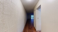 Located at 3438 E Fourth St in Tucson, Arizona, this single-floor unit offers a practical and well-organized layout with a variety of thoughtful interior details throughout. An entry hallway with rich, dark hardwood flooring leads into the main living area, where a ceiling fan overhead and built-in wall shelving add both function and character. The open-concept living and dining area is generously proportioned, featuring the same warm hardwood floors and a sliding glass door that invites natural light while providing access to an outdoor area. The kitchen is efficiently designed in an L-shaped configuration, equipped with dark wood cabinetry, granite-toned countertops, a double basin sink, white appliances including a coil-top range, dishwasher, and a pass-through window connecting to the main living space. Two bathrooms are present: one featuring a tub-shower combo with tiled surround and granite-style vanity countertop, and a second with similar finishes. The bedrooms are carpeted for comfort, with one room offering sliding glass door access to the outdoors and another featuring a built-in closet with a rod and shelving. Textured ceilings are consistent throughout, contributing to the unit's cohesive aesthetic.