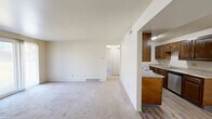 Located at 4363 Chestnut Ridge Rd in Buffalo, NY, this single-floor unit offers a practical and functional layout across one bedroom and two bathrooms. The galley-style kitchen is lined with rich, dark wood cabinetry paired with light granite-style countertops, providing generous storage and prep space. Light wood-tone vinyl flooring runs throughout the kitchen, which is equipped with a white electric range, refrigerator, and dishwasher. A ceiling fan overhead and an open view into the adjoining living area give the kitchen an airy, connected feel. The spacious bedroom features soft wall-to-wall carpeting and a large window dressed with vertical blinds, allowing natural light to filter in. Multiple closet doors offer ample storage within the bedroom. The two bathrooms are clean and well-appointed; one features a full soaking tub and shower combination with a white surround, built-in corner shelving, and a safety grab bar, while the other includes a white vanity with an integrated sink and a large mirror. Neutral wall tones and consistent finishes throughout lend the space a cohesive, move-in-ready appearance, making it a practical and comfortable home.