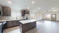 Located at 13565 Bonanza Cir in Cresson, TX, this single-story home offers a clean, modern design across three bedrooms and three bathrooms. The open-concept living room features vaulted ceilings, recessed lighting, a ceiling fan, and light wood-look flooring that flows throughout the main living areas, creating a bright and airy atmosphere. Large windows invite natural light and provide views of the surrounding neighborhood.

The kitchen is a standout feature, showcasing dark espresso cabinetry, a neutral tile backsplash, stainless steel appliances, and a central island with a crisp white countertop — ideal for both cooking and entertaining. The kitchen opens seamlessly to the living area, reinforcing the home's open feel.

The spacious primary bedroom benefits from vaulted ceilings, a ceiling fan, and a large window with outdoor views, while a generous walk-in closet with built-in shelving and hanging rods provides ample storage. Additional bedrooms share the same light flooring and vaulted ceiling design. The bathrooms are finished with tile flooring, dark-framed fixtures, and clean white vanities. A dedicated laundry room with side-by-side washer and dryer hookups adds everyday convenience. The attached garage includes a water heater and electrical panel, completing this well-appointed home.