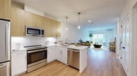 Located at 5545 Park Ave in Fairfield, CT, this well-designed 2-bedroom, 1-bathroom residence offers a thoughtful open-concept floor plan with modern finishes throughout. Light hardwood flooring flows seamlessly across the main living areas, complementing the bright, neutral color palette that creates an airy and welcoming atmosphere.

The kitchen is a standout feature, boasting white lower cabinetry paired with warm natural wood upper cabinets, a white quartz peninsula with seating, stainless steel appliances including a range, microwave, dishwasher, and refrigerator, a subway tile backsplash, and stylish pendant lighting. The kitchen opens directly into the living room, which is bathed in natural light from a sliding glass door leading to a private balcony with outdoor views.

The spacious primary bedroom features large windows with leafy green views, light hardwood floors, and a clean, restful aesthetic. A versatile den provides additional flexible space ideal for a home office or reading room. The bathroom is finished with neutral tile flooring, a white vanity with a large mirror, and a walk-in glass shower. Additional conveniences include a dedicated laundry room, a closet, and a utility room, making this a fully functional and comfortable home.