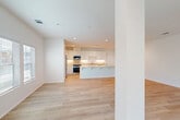 Located at 55150 Monroe St in La Quinta, California, this single-story home offers a clean, modern aesthetic throughout its well-appointed floor plan. The interior is defined by light wood-tone flooring, crisp white walls, and recessed lighting that create a bright and cohesive atmosphere across every room.

The open-concept living and dining area is expansive and airy, anchored by a ceiling fan and windows fitted with blinds that allow natural light to fill the space. It flows seamlessly into the kitchen, which features an extended peninsula with a light quartz countertop, white shaker cabinetry reaching to the ceiling, under-cabinet lighting, and a full suite of stainless steel appliances. A pantry provides additional storage, further enhancing the kitchen's functionality.

The generously sized primary bedroom includes ample closet space. Its en-suite bathroom is finished with a dual-sink vanity, warm-toned countertops, white cabinetry, and a glass-enclosed walk-in shower. Additional bathrooms are well-appointed, with at least one featuring a full tub-shower combination. Two additional bedrooms each include ceiling fans and window access to natural light.

The home also includes a dedicated office, a laundry room, and multiple walk-in closets with built-in shelving. A connected garage completes this thoughtfully designed La Quinta residence.