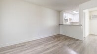 This 520 square foot apartment in Fullerton, CA offers a blend of modern aesthetics and practical living. The space is efficiently designed with an open-concept layout, maximizing the use of its single-floor plan. The main living area boasts sleek wood-look flooring, creating a contemporary ambiance. Large windows with vertical blinds allow ample natural light, enhancing the sense of spaciousness.

The bedroom features plush carpeting for comfort, while a ceiling fan provides additional climate control. The bathroom has been updated with modern fixtures and continues the wood-look flooring theme. A compact kitchen with white cabinetry and a countertop bar area efficiently utilizes the space.

Throughout the apartment, crisp white walls create a bright, clean canvas. The property includes air conditioning for year-round comfort. Storage solutions are integrated, with built-in closets visible in the hallway. This apartment offers a cozy yet functional living space, ideal for those seeking a modern, low-maintenance home in a prime location.