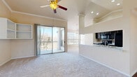 Located at 801 Legacy Dr in Plano, TX, this well-designed 2-bedroom, 2-bathroom residence offers a thoughtful single-level floor plan that maximizes both comfort and functionality. The living area immediately impresses with soaring vaulted ceilings, crown molding, and a ceiling fan that enhances the sense of openness. Plush carpeting runs throughout the main living space, and sliding glass doors lead to a private balcony, flooding the room with natural light and offering pleasant outdoor views. Built-in wall shelving adds a practical decorative touch to the living area. The kitchen is a standout feature, boasting dark espresso cabinetry, mosaic tile backsplash, light granite-style countertops, black appliances, and rich hardwood-style flooring. A peninsula counter opens the kitchen seamlessly to the living space, ideal for casual dining or entertaining. The spacious primary bedroom includes vaulted ceilings, a ceiling fan, abundant natural light from large windows, and a generous walk-in closet with built-in shelving. The second bedroom is equally well-lit with ample closet space. Both bathrooms feature tub-shower combinations, hardwood-style flooring, and clean white finishes, with the primary bath offering a sliding glass-door enclosure.
