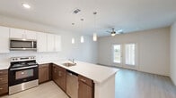 Located at 2700 E Howard Lane in Manor, TX, this well-appointed one-bedroom, one-bathroom residence offers a thoughtfully designed open-concept floor plan. Light wood-style flooring flows seamlessly throughout the space, complementing the clean, neutral color palette and modern aesthetic.

The kitchen is a standout feature, showcasing a large peninsula with white quartz countertops, two-tone cabinetry with rich walnut-finish lower cabinets and crisp white upper cabinets, a white subway tile backsplash, stainless steel appliances including a range, microwave, dishwasher, and refrigerator, and stylish pendant lighting overhead. The kitchen opens directly into the living area, which is brightened by natural light from a set of French doors and includes a ceiling fan.

The spacious primary bedroom offers a comfortable layout with a ceiling fan and a window with outdoor views. It connects to a full bathroom featuring a single-sink vanity with a walnut-finish cabinet, a soaking tub with shower, and direct access to a dedicated walk-in closet complete with built-in wire shelving. This residence combines modern finishes with a functional layout, making it an efficient and attractive living space in the Manor, TX area.