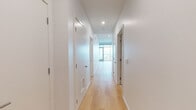 Located at 200 Ocean in Long Beach, California, this modern single-floor residence offers a clean, contemporary design throughout. The open living area is defined by expansive floor-to-ceiling glass walls that flood the space with natural light and frame sweeping panoramic views of the Long Beach skyline and beyond, with a sliding glass door providing access to the outdoors. Light-toned hardwood flooring runs continuously through the living spaces, enhancing the bright, airy atmosphere.

The kitchen is thoughtfully designed with a seamless blend of white upper cabinetry and warm natural wood lower cabinets, complemented by light stone countertops, under-cabinet lighting, and stainless steel appliances including a gas range, built-in microwave, dishwasher, and refrigerator.

A well-lit hallway with recessed lighting connects the living areas to the private rooms, maintaining the home's clean aesthetic. The bathrooms continue the modern design language, featuring large-format light tile flooring, glass-enclosed showers, wall-mounted toilets, and floating wood vanities topped with white countertops and framed mirrors. Every detail reflects a precise, minimalist approach to contemporary residential design.