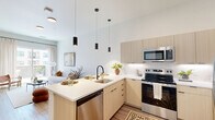 Located at 514 S Weber St in Colorado Springs, CO, this thoughtfully designed one-bedroom, one-bathroom residence offers a contemporary living experience across a single well-organized floor. The open-concept kitchen and living area serves as the heart of the unit, where light wood cabinetry, white subway tile backsplash, and a full suite of stainless steel appliances — including a refrigerator, electric range, and microwave — combine for a clean, modern aesthetic. A peninsula island with seating and striking black pendant lighting overhead provides both additional prep space and a casual dining option. Wide-plank wood-style flooring runs throughout, lending warmth and continuity. The living area is bright and airy, with large sliding glass doors drawing in natural light and providing access to a private outdoor space. The bedroom offers a calm, minimalist retreat with neutral tones, tall ceilings, and ample closet storage across two dedicated closets. The bathroom is clean and functional, featuring a light wood vanity, a tub-shower combination, and a standout convenience — an in-unit stacked washer and dryer tucked neatly into an adjacent closet. The overall design balances modern finishes with a warm, livable atmosphere throughout.