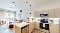 Located at 514 S Weber St in Colorado Springs, CO, this thoughtfully designed one-bedroom, one-bathroom residence offers a contemporary living experience across a single well-organized floor. The open-concept kitchen and living area serves as the heart of the unit, where light wood cabinetry, white subway tile backsplash, and a full suite of stainless steel appliances — including a refrigerator, electric range, and microwave — combine for a clean, modern aesthetic. A peninsula island with seating and striking black pendant lighting overhead provides both additional prep space and a casual dining option. Wide-plank wood-style flooring runs throughout, lending warmth and continuity. The living area is bright and airy, with large sliding glass doors drawing in natural light and providing access to a private outdoor space. The bedroom offers a calm, minimalist retreat with neutral tones, tall ceilings, and ample closet storage across two dedicated closets. The bathroom is clean and functional, featuring a light wood vanity, a tub-shower combination, and a standout convenience — an in-unit stacked washer and dryer tucked neatly into an adjacent closet. The overall design balances modern finishes with a warm, livable atmosphere throughout.