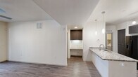 This well-appointed single-floor residence offers three bedrooms, one bathroom, a dedicated laundry room, and three closets across a thoughtfully designed layout. Wood-look plank flooring flows consistently throughout the home, complementing the clean, neutral color palette and modern aesthetic.

The open-concept kitchen and living area serves as the heart of the home. The kitchen features dark cabinetry, granite-look countertops, subway tile backsplash, stainless steel appliances including a refrigerator with ice and water dispenser, and pendant lighting. The adjacent living area includes a ceiling fan and connects seamlessly to the entry.

Each of the three bedrooms is finished with wood-look flooring, ceiling fans, and window blinds that allow natural light while maintaining privacy. The generously sized primary bedroom includes a walk-in closet with built-in shelving and hanging rods for ample storage. Additional closets provide further organizational flexibility throughout the home.

The full bathroom is outfitted with a long vanity topped with a white countertop, dark lower cabinetry, a large mirror, and contemporary light fixtures. The dedicated laundry room accommodates a full-size side-by-side washer and dryer with overhead shelving. A textured ceiling and consistent trim details complete the refined, modern character of this functional residence.