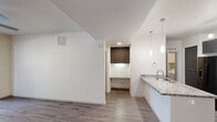 This well-appointed single-floor residence offers three bedrooms, one bathroom, a dedicated laundry room, and three closets across a thoughtfully designed layout. Wood-look plank flooring flows consistently throughout the home, complementing the clean, neutral color palette and modern aesthetic.

The open-concept kitchen and living area serves as the heart of the home. The kitchen features dark cabinetry, granite-look countertops, subway tile backsplash, stainless steel appliances including a refrigerator with ice and water dispenser, and pendant lighting. The adjacent living area includes a ceiling fan and connects seamlessly to the entry.

Each of the three bedrooms is finished with wood-look flooring, ceiling fans, and window blinds that allow natural light while maintaining privacy. The generously sized primary bedroom includes a walk-in closet with built-in shelving and hanging rods for ample storage. Additional closets provide further organizational flexibility throughout the home.

The full bathroom is outfitted with a long vanity topped with a white countertop, dark lower cabinetry, a large mirror, and contemporary light fixtures. The dedicated laundry room accommodates a full-size side-by-side washer and dryer with overhead shelving. A textured ceiling and consistent trim details complete the refined, modern character of this functional residence.