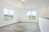 Located on Boneset Ave in Poynette, Wisconsin, this two-story home offers generous living space across two well-appointed floors. The main level is expansive, housing a combined kitchen and living area that serves as the heart of the home. The modern kitchen is a standout feature, equipped with stainless steel appliances including a range with a sleek hood vent, a French door refrigerator, and a dishwasher. White quartz countertops extend across a large central island with a double undermount sink, complemented by open wood shelving, a gray subway tile backsplash, and stylish pendant lighting. Light wood-tone flooring flows throughout, enhancing the bright, clean aesthetic established by the crisp white walls and trim. The main level also features a large room with polished concrete flooring, ideal for flexible use. Upstairs, the second floor hosts the remaining bedrooms, including a remarkably generous primary bedroom. Bedrooms are finished with light wood-tone flooring and large windows that invite natural light and offer peaceful views of the surrounding neighborhood and a nearby pond. The two bathrooms are clean and functional — one featuring a tub/shower combo and the other a walk-in shower with grab bar. A carpeted staircase with a sleek metal handrail connects both levels, completing this well-designed home.
