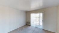 Unit #349 at 2525 Highland in National City is a single-floor residence designed with simplicity and functionality in mind. The living area is a welcoming, open space finished with wall-to-wall carpeting that adds warmth underfoot. A full-width sliding glass door floods the room with natural light and provides direct access to a private balcony, offering outdoor views of the surrounding neighborhood. Vertical blinds offer adjustable light control and privacy throughout the day. The walls are painted in a clean, neutral tone that enhances the brightness of the space, while a textured ceiling adds a subtle architectural detail overhead. A wall-mounted HVAC unit ensures climate comfort year-round. The overall ambiance is light, airy, and move-in ready, presenting a clean canvas well-suited for personalization. The single-floor layout offers ease of accessibility, making everyday living straightforward and convenient. This unit combines practical features with a modest, comfortable atmosphere in a residential setting in National City.
