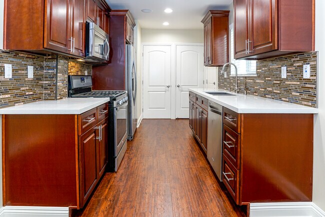 Cocina con encimera de cuarzo con salpicadura de vidrio negro y gabinetes de cierre suave. - 7522 Fountain Ave