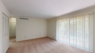 This single-floor residence in Davison, Michigan offers a practical and well-organized layout across three bedrooms, a kitchen, hallway, and closet. The living area is a standout feature, showcasing warm neutral-toned carpeting and a full-width sliding glass door dressed with vertical blinds that floods the space with natural light and provides direct outdoor views — a bright and welcoming focal point of the home. The primary bedroom is generously sized, offering ample room for furnishings, and is carpeted to match the rest of the living spaces. The additional bedrooms are cozy and functional, each featuring windows with horizontal blinds that bring in natural light. The kitchen is laid out in a galley style, featuring a mix of wood-toned and white cabinetry, light countertops, a stainless steel sink, and white appliances including a refrigerator and electric range. Hardwood-style flooring in the kitchen adds a warm contrast to the carpeted rooms. Throughout the unit, clean white walls, consistent neutral tones, and understated finishes create a calm, move-in-ready atmosphere. The hallway connects the rooms efficiently, and a dedicated closet provides additional storage.