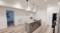 Located at 900 N Leverette Ave in Fayetteville, Arkansas, this one-bedroom unit offers a well-designed single-floor layout that balances modern finishes with functional living. Light wood-style luxury flooring runs throughout the main living and kitchen areas, creating a clean, cohesive aesthetic.

The kitchen is a standout feature, equipped with gray shaker-style cabinetry, granite countertops, and a classic white tile backsplash. A central island with a built-in sink and pendant lighting above adds both workspace and visual appeal. Black appliances, including a full-size refrigerator, gas range, and microwave, complete the kitchen's practical setup. Recessed lighting throughout ensures a bright, well-lit environment.

The spacious bedroom is finished with plush carpet, two windows that invite natural light and outdoor greenery views, and a ceiling fan for year-round comfort. An en-suite bathroom is accessible directly from the bedroom, adding convenience. Additional windows in the living area further enhance the unit's natural light.

The overall design features crisp white walls, clean lines, and modern fixtures, creating a fresh and contemporary atmosphere throughout this thoughtfully laid-out Fayetteville residence.
