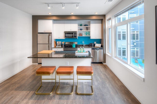 Kitchen with white cabinetry, granite countertops, island, stainless steel appliances and hard surface flooring - AVA Wheaton