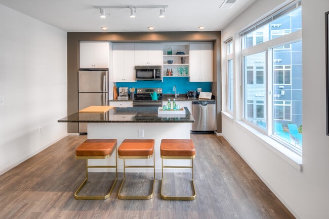 Kitchen with white cabinetry, granite countertops, island, stainless steel appliances and hard surface flooring - AVA Wheaton