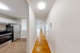 Located at 735 Adams St, Unit 411 in Boston's Dorchester neighborhood, this two-bedroom, one-bathroom residence offers a well-organized single-floor layout with clean, modern finishes throughout. Warm hardwood floors run through the hallway, living room, and both bedrooms, creating a cohesive and inviting atmosphere. The central hallway connects all areas of the home efficiently, with natural light visible at the far end leading to the living space. The living room is generously proportioned, featuring a sliding glass door that fills the room with natural light and provides an outdoor view, complemented by baseboard heating. The kitchen is well-appointed with warm honey-toned cabinetry, dark granite-style countertops, and a full suite of stainless steel appliances including a refrigerator, electric range, and dishwasher. Light wood-look flooring and a pass-through opening to the living area enhance the kitchen's functional design. Both bedrooms are bright and comfortably sized, each featuring recessed lighting, closet access, and baseboard heating. The primary bedroom benefits from a dedicated closet. The bathroom is finished in white tile with a tub/shower combination and a vanity with mirror. Notably, the unit offers an impressive seven closets, providing exceptional storage throughout.