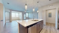 Located at 9357 Old Union Rd in Union, Kentucky, this well-appointed 2-bedroom, 2-bathroom single-floor residence offers a thoughtfully designed open-concept layout. The kitchen and living area flow seamlessly together, anchored by a central island featuring a double-basin sink, stainless steel dishwasher, and elegant pendant lighting. The kitchen is further equipped with full-height cabinetry in a warm taupe finish, white quartz countertops, a subway tile backsplash, and a full suite of stainless steel appliances including a refrigerator, range, and microwave. Light wood-look flooring spans the main living and kitchen areas, while a ceiling fan enhances the bright, airy living room, which benefits from multiple windows allowing generous natural light. The primary bedroom is a comfortable retreat with wood-look flooring, accompanied by an en-suite bathroom featuring a single-sink vanity with quartz countertop, tile-surround walk-in glass shower, and a walk-in closet. The second bedroom is carpeted and well-lit with large windows offering outdoor views. Additional spaces include a dedicated laundry area and a utility closet housing a modern water heater system. The overall ambiance is clean, contemporary, and move-in ready.