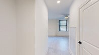 Located at 142 West York in Norfolk, VA, this efficiently designed single-floor unit delivers a clean, modern aesthetic throughout. The open layout makes excellent use of its footprint, with light-toned luxury vinyl flooring running seamlessly across the main living areas, contributing to a bright and cohesive feel.

The kitchen is a standout feature, equipped with a full suite of stainless steel appliances — including a refrigerator, electric range, microwave, and dishwasher — paired with crisp white shaker-style cabinetry that extends to the ceiling for ample storage. A bold dark tile backsplash provides striking contrast against the white cabinetry and dark countertops, lending the kitchen a polished, contemporary character.

The main room is well-lit by dual black-framed windows that invite natural light, and is outfitted with a ceiling fan for added comfort. Recessed lighting throughout ensures consistent illumination. A dedicated entrance with a dark-accented door adds a sense of arrival to the space.

The bathroom features a full soaking tub and shower combination with distinctive matte black fixtures and hardware, set against a clean all-white surround. A walk-in closet with built-in shelving provides practical storage. The unit's neutral white walls and modern finishes throughout create a fresh, move-in ready environment.