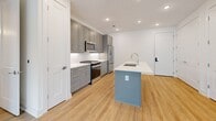 Located in Alpharetta, GA, this thoughtfully designed 2-bedroom, 2-bathroom residence offers a clean, modern aesthetic with consistent hardwood-style flooring and crisp white walls throughout. The open-concept kitchen serves as the heart of the home, showcasing gray shaker cabinetry extending to the ceiling, white subway tile backsplash, stainless steel appliances including a gas range and French door refrigerator, and a central island with a white quartz countertop and undermount sink — ideal for cooking and entertaining. The spacious primary bedroom features a ceiling fan, dual windows that invite abundant natural light, and direct access to a well-appointed en-suite bathroom. The primary bath includes a gray vanity with quartz countertop, a large frameless mirror, and a glass-enclosed walk-in shower tiled in classic white subway tile, alongside a generous walk-in closet outfitted with wire shelving. The second bedroom mirrors the bright, airy feel with dual windows and light-filled interiors. Both bathrooms carry the same cohesive design language with gray cabinetry and quartz surfaces. Recessed lighting, clean baseboards, and a neutral palette contribute to a polished, move-in-ready atmosphere throughout.