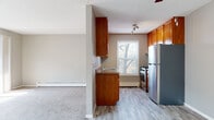 This single-floor unit offers a practical and comfortable layout with clearly defined living spaces throughout. The galley-style kitchen is efficiently arranged, featuring warm wood cabinetry that extends to the ceiling for ample storage, a double-basin sink, dark laminate countertops, and a full suite of stainless steel appliances including a gas range and refrigerator. Light wood-tone vinyl flooring runs through the kitchen, and a window above the baseboard heater allows natural light to filter in with exterior views of mature trees.

The living area is generously proportioned, finished with neutral gray carpet and open enough to accommodate a variety of furniture arrangements. A hallway connects the main living space to the rest of the unit. A sliding glass door leads to a private balcony, filling the room with natural light and providing outdoor access. A wall-mounted air conditioning unit and baseboard heating ensure year-round comfort.

The bedrooms are carpeted and well-lit, each featuring windows with vertical blinds, baseboard heating, and wall-mounted AC units. Both bathrooms are consistently finished with wood-toned vanities, white countertops, mirrored medicine cabinets, and wood-look vinyl flooring. One bathroom includes a full tub-shower combination.