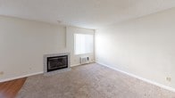 Located at 744 W Fallbrook, Unit #51 is a well-laid-out single-story residence that balances comfort and practicality throughout its interior spaces. The living room serves as the heart of the home, highlighted by a tile-surround fireplace with glass doors, plush wall-to-wall carpeting, and a window fitted with vertical blinds that allows natural light to filter in. A wall-mounted air conditioning unit provides convenient climate control. The galley-style kitchen is efficiently designed with rich, dark wood cabinetry lining both walls, granite-style countertops, a stainless sink, and white appliances including a gas range, dishwasher, and refrigerator. Wood-look flooring runs throughout the kitchen, adding warmth and easy maintenance. The bedrooms are generously proportioned, each featuring soft carpeting and neutral walls, with windows bringing in natural light. The bathrooms are well-appointed; the full bath includes a tub-shower combo with tile surround, wood-look flooring, a rich wood vanity with granite-style countertop, and a lighted mirror. A second bathroom features matching wood cabinetry and dark wood-look flooring. The textured ceilings and clean, neutral color palette throughout lend the space a cohesive, move-in-ready feel.