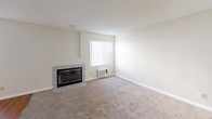 Located at 744 W Fallbrook, Unit #51 is a well-laid-out single-story residence that balances comfort and practicality throughout its interior spaces. The living room serves as the heart of the home, highlighted by a tile-surround fireplace with glass doors, plush wall-to-wall carpeting, and a window fitted with vertical blinds that allows natural light to filter in. A wall-mounted air conditioning unit provides convenient climate control. The galley-style kitchen is efficiently designed with rich, dark wood cabinetry lining both walls, granite-style countertops, a stainless sink, and white appliances including a gas range, dishwasher, and refrigerator. Wood-look flooring runs throughout the kitchen, adding warmth and easy maintenance. The bedrooms are generously proportioned, each featuring soft carpeting and neutral walls, with windows bringing in natural light. The bathrooms are well-appointed; the full bath includes a tub-shower combo with tile surround, wood-look flooring, a rich wood vanity with granite-style countertop, and a lighted mirror. A second bathroom features matching wood cabinetry and dark wood-look flooring. The textured ceilings and clean, neutral color palette throughout lend the space a cohesive, move-in-ready feel.