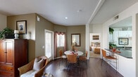 This thoughtfully designed 2-bedroom, 2-bathroom residence is laid out across a single floor, offering a practical and comfortable living environment. The combined living and dining area forms the heart of the home, featuring rich dark hardwood flooring, warm taupe-toned walls, and a ceiling fan that enhances airflow and comfort. Natural light filters in through windows dressed with decorative curtains, creating an inviting atmosphere. The dining area connects seamlessly to the kitchen via a pass-through counter, making the layout ideal for everyday living and entertaining.

The kitchen is well-equipped, featuring white cabinetry with ample storage, dark granite-style countertops, white appliances including a range, microwave, and double-basin sink, all set on dark hardwood flooring. The entry hallway transitions between tile and carpet, providing a clear boundary between spaces.

Both bedrooms are carpeted and bathed in natural light, with the primary bedroom offering generous proportions and its own closet. A second walk-in closet with wire shelving provides additional storage. The bathrooms are clean and functional, each featuring a shower-tub combination. Overall, the residence presents a cohesive, warm aesthetic with practical finishes throughout.