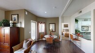 This thoughtfully designed 2-bedroom, 2-bathroom residence is laid out across a single floor, offering a practical and comfortable living environment. The combined living and dining area forms the heart of the home, featuring rich dark hardwood flooring, warm taupe-toned walls, and a ceiling fan that enhances airflow and comfort. Natural light filters in through windows dressed with decorative curtains, creating an inviting atmosphere. The dining area connects seamlessly to the kitchen via a pass-through counter, making the layout ideal for everyday living and entertaining.

The kitchen is well-equipped, featuring white cabinetry with ample storage, dark granite-style countertops, white appliances including a range, microwave, and double-basin sink, all set on dark hardwood flooring. The entry hallway transitions between tile and carpet, providing a clear boundary between spaces.

Both bedrooms are carpeted and bathed in natural light, with the primary bedroom offering generous proportions and its own closet. A second walk-in closet with wire shelving provides additional storage. The bathrooms are clean and functional, each featuring a shower-tub combination. Overall, the residence presents a cohesive, warm aesthetic with practical finishes throughout.