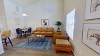 This single-floor unit makes a strong architectural impression with its dramatic vaulted ceilings, which lend an airy, open feel well beyond what its footprint might suggest. The combined kitchen and living room serves as the heart of the space, where natural light streams in through large, blinds-fitted windows. The living area accommodates a comfortable seating arrangement beneath the soaring ceiling, creating a spacious atmosphere enhanced by neutral walls and wood-look plank flooring.

The kitchen is well-appointed with rich dark espresso cabinetry extending nearly to the ceiling, granite-style countertops, a full suite of black appliances including a refrigerator, range, dishwasher, and microwave, and a peninsula with seating that doubles as a casual dining surface. A pendant light anchors the kitchen visually, and the layout offers generous counter and storage space.

The bedroom is a comfortably sized private retreat, finished with plush carpet, a ceiling fan, and a window with natural light. It connects directly to a dedicated closet featuring built-in shelving and a hanging rod. Throughout, the unit balances functional design with architectural character, particularly through its prominent vaulted ceiling in the main living area.