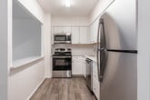 Located at 6 Summit St in West Orange, NJ, this single-floor unit offers a clean, modern aesthetic throughout its well-organized layout. The kitchen is a standout feature, equipped with stainless steel appliances including a refrigerator, range, microwave, and dishwasher. White shaker-style cabinetry extends to the ceiling, providing generous storage, while a classic subway tile backsplash and a large quartz peninsula with bar seating add both style and functionality. Light wood-look flooring runs through the kitchen, creating a bright and welcoming atmosphere. The bedrooms are carpeted for comfort and maintain a neutral, airy palette. One bedroom features a large window with natural light and a wall-mounted air conditioning unit alongside baseboard heating, while another offers expansive built-in closet space with full-width bi-fold doors. The bathroom is thoughtfully updated with marble-look tile flooring, a floating white vanity with under-cabinet storage, a mirrored medicine cabinet, and modern fixtures. The overall design of the space is cohesive and understated, emphasizing clean lines, bright white tones, and practical finishes throughout.