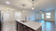 Located at 1025 Retreat Dr. in Bartow, Florida, this single-story, one-bedroom, one-bathroom home offers a well-designed open-concept layout that maximizes every inch of its comfortable living space. Light-toned wood-style flooring flows throughout the main living areas, complementing the bright, neutral walls and modern finishes.

The kitchen is a standout feature, showcasing rich dark-espresso cabinetry, a full suite of stainless steel appliances, and a granite-topped island with an undermount sink and pendant lighting overhead — ideal for both cooking and casual dining. The kitchen opens seamlessly into the living room, which benefits from natural light through a glass-panel entry door and a ceiling fan overhead.

The spacious primary bedroom features plush carpeting, a ceiling fan, and direct access to the bathroom. The bathroom is well-appointed with a granite vanity, dark cabinetry, and a large walk-in shower finished with marble-style tile surround and a sleek glass enclosure.

Additional highlights include a walk-in closet with wire shelving systems offering ample storage, and a dedicated laundry room equipped with washer/dryer hookups and overhead shelving. The home presents a clean, contemporary aesthetic throughout, making it a functional and attractive residence in Bartow, FL.