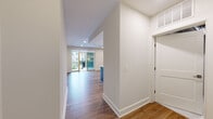 This well-appointed single-floor residence showcases a thoughtful open-concept layout that seamlessly connects the living and kitchen areas. Wide-plank hardwood flooring flows throughout the main living spaces, lending warmth and continuity to the design. The kitchen is a standout feature, centered around a bold navy blue island with a white quartz countertop and integrated sink. White upper cabinetry, dark lower cabinets, a marble-look tile backsplash, stainless steel appliances including a gas range and refrigerator, and recessed lighting complete the contemporary aesthetic. The living area is generously proportioned, with access to a private balcony through sliding glass doors that invite natural light into the space. Bedrooms offer hardwood flooring and windows with outdoor views. The primary suite connects to a sleek en-suite bathroom finished with marble-look floor and wall tiles, a dark-toned vanity with white countertop, and a tiled shower surround. An additional bathroom mirrors the same refined finishes. A spacious walk-in closet with wire shelving provides ample storage. A dedicated laundry closet houses a stacked washer and dryer unit. Clean white walls, crisp millwork, and recessed lighting throughout contribute to a bright, modern ambiance.