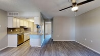 This single-floor unit offers a thoughtfully designed open-concept layout that seamlessly connects the kitchen and living area. The kitchen is well-equipped with white cabinetry, granite countertops, a subway tile backsplash, stainless steel appliances including a dishwasher and range, and a peninsula that provides additional prep space and serves as a natural divider between the kitchen and living area. Wood-style flooring runs throughout the main living spaces, adding warmth and continuity to the interior.

The living area is generously sized, featuring a ceiling fan with a light fixture and a front entry door flanked by a window that allows natural light to fill the room. Neutral gray walls provide a clean, versatile backdrop throughout the unit.

The bedroom is a comfortable and well-lit space, featuring its own ceiling fan, a window offering natural light, and access to a walk-in closet. The full bathroom includes a granite-topped vanity with white cabinetry, a framed mirror, and a tub-shower combination with white tile surround. A textured ceiling is consistent throughout the unit, complementing the overall practical and clean aesthetic of the space.