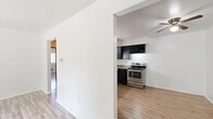This 2-bedroom, 1-bathroom residence offers a functional and efficient single-floor layout. Light wood-style flooring flows consistently throughout, lending a clean, cohesive feel to every room.

The living room is a bright, welcoming space anchored by a sliding glass door that opens onto a private balcony overlooking lush, mature trees — filling the room with generous natural light. The kitchen is well-equipped, featuring dark shaker-style cabinetry, light stone-look countertops, and a full suite of stainless steel appliances including an electric range, dishwasher, and built-in microwave. The layout maximizes counter and storage space efficiently.

Both bedrooms are comfortably sized, with the primary bedroom offering a ceiling fan and a built-in sliding-door closet for ample storage. The second bedroom is similarly bright and airy, with clean white walls and easy access to the hallway. The shared bathroom includes a full tub and shower combination, finished with neutral large-format tile surround for a classic, clean aesthetic.

A connecting hallway ties the space together, providing smooth flow between rooms. Throughout, the design is straightforward and practical, offering a clean, move-in-ready environment suited for everyday living.