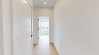 This thoughtfully designed residence in Revere, MA offers three bedrooms and two full bathrooms across a single floor. The interior showcases a clean, modern aesthetic defined by crisp white walls, light wood flooring throughout, and black hardware accents that provide a contemporary contrast.

The open kitchen is a standout feature, centered around a large white island with a sleek matte black faucet and pendant lighting overhead. Cabinetry is finished in a soft neutral tone, complemented by a tile backsplash and stainless steel appliances including a refrigerator, microwave, and range.

Each bedroom is bright and airy, benefiting from large windows that invite generous natural light. The primary bedroom offers views of the surrounding Revere neighborhood rooftops and skyline. One bedroom includes a double sliding closet, while another features floor-to-ceiling windows with urban views.

The two bathrooms are finished in a clean, minimal style. One includes a full soaking tub with white tile surround and chrome fixtures, while the second features a glass-enclosed walk-in shower with matching white tile. Both bathrooms continue the light, neutral palette established throughout the home.

A connecting hallway ties the layout together, creating a functional and cohesive flow between all rooms.