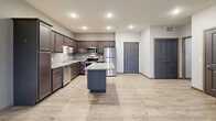 Located at 1160 Suncrest Dr in Saint Cloud, MN, this single-floor, one-bedroom, one-bathroom unit offers a well-planned layout across a comfortable footprint. The kitchen is a standout feature, showcasing rich dark-wood cabinetry extending to the ceiling, granite countertops, a central island with additional counter space, and a full suite of stainless steel appliances including a refrigerator, range, microwave, and dishwasher. Light hardwood-style flooring runs throughout the kitchen and entry areas, creating a clean transition into the living room. The spacious living room is carpeted and bathed in natural light, with a sliding door leading to a private balcony and a wall-mounted HVAC unit for climate control. Baseboard heating is present throughout the unit. The generously sized primary bedroom features plush carpeting, a large window with outdoor views, and ample wall space for furnishings. The bathroom is well-appointed with dark wood vanity cabinetry, a wide vanity mirror, stylish light fixture, solid-surface countertop, and stone-look tile flooring. A dedicated closet and hallway complete the layout, offering practical storage and connectivity between rooms. Neutral gray walls and recessed lighting lend the space a modern, move-in-ready feel.