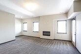 This well-appointed single-floor unit offers a thoughtfully designed open-concept layout that seamlessly connects the living, dining, and kitchen areas. The living room is generously sized, featuring plush carpet flooring, multiple windows with blinds that invite natural light, and a sleek built-in electric fireplace that serves as a focal point of the room.

The kitchen is a standout feature, equipped with rich dark espresso cabinetry, dark granite countertops, and a full suite of stainless steel appliances including a French door refrigerator, electric range, over-the-range microwave, and dishwasher. A kitchen island with pendant lighting overhead adds both functionality and style, while wood-look plank flooring runs throughout the kitchen and connecting areas.

The bedrooms are carpeted and well-lit, each featuring windows with outdoor views and ample wall space for furnishings. The bathroom is finished with dark espresso cabinetry, a granite vanity countertop, an undermount sink, a large mirror, and tile flooring. A wall-mounted grab bar indicates accessibility-conscious design. A dedicated laundry room with a full-size washer and dryer and overhead shelving adds everyday convenience. The cohesive dark-toned finishes throughout give the space a modern, polished aesthetic.