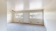 Located at 2427 W Garrison Ave in Baltimore, MD, this single-floor residence offers a practical and straightforward layout spread across several distinct areas. The spacious main living area is carpeted in neutral tones and features multiple large windows that allow generous natural light to fill the room, offering views of the surrounding neighborhood. A ceiling fan provides year-round comfort, and multiple floor vents support an efficient HVAC system throughout.

The layout includes additional carpeted rooms, each finished with neutral walls and clean white baseboards. One room features a built-in closet with bifold doors, providing useful storage, while another smaller room includes a window and overhead light fixture. An entry area with hard flooring provides a transition point into the living spaces.

The kitchen is equipped with warm oak cabinetry, dark granite-style countertops, and a full suite of black appliances including a gas range, dishwasher, and refrigerator. Light wood-look flooring adds a clean, durable finish to this functional cooking space.

The bathroom is well-appointed with a tiled tub-and-shower combination, a wood-vanity with a white countertop, a mirrored medicine cabinet, and classic mosaic tile flooring, delivering a tidy and practical design throughout.