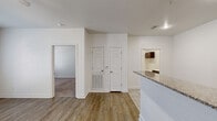 Located in North Little Rock, AR, this one-bedroom, one-bathroom residence offers a thoughtfully designed single-floor layout that maximizes functionality and comfort. The open-concept living room serves as the heart of the home, featuring warm wood-look vinyl flooring, a ceiling fan with light fixture, and French doors that invite natural light and provide outdoor access. The space flows seamlessly into the kitchen, which is separated by a breakfast bar with granite-look countertops. The kitchen is well-equipped with dark espresso cabinetry, matching granite-look countertops, black appliances including a range and refrigerator, and light tile flooring that ties the cooking space together cleanly. The bedroom is generously sized with plush carpeting, a ceiling fan, and a window for natural light. It connects directly to a spacious walk-in closet outfitted with wire shelving for efficient storage. The bathroom maintains the same cohesive design language, featuring tile flooring, dark cabinetry with a vanity, and a wall-mounted storage cabinet. Throughout the residence, clean white walls, consistent trim work, and recessed lighting create a bright, neutral ambiance that is both inviting and easy to personalize.