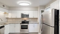 Located at 4506 Staffordshire Dr in Wilmington, NC, this single-floor home offers a clean, modern aesthetic throughout with a neutral warm-gray color palette and consistent luxury vinyl plank flooring that runs seamlessly across every room.

The kitchen is a standout feature, thoughtfully designed with white shaker-style cabinetry, granite-look countertops, a classic subway tile backsplash, and a full suite of stainless steel appliances including a refrigerator, range, over-the-range microwave, and dishwasher. Ample cabinetry provides generous storage, and a window allows natural light to fill the space.

The open layout connects the kitchen to the living and dining areas, creating a cohesive flow ideal for everyday living and entertaining. The living area features sliding glass doors that open directly to a private, fenced backyard, bringing in natural light and outdoor views.

The bedrooms are well-proportioned, each featuring light-filled windows with blinds and the same consistent flooring. One room includes in-unit laundry with a full-size washer and dryer tucked behind bifold doors alongside closet storage.

The bathroom is finished with a white vanity, a mirrored medicine cabinet, and clean, bright fixtures. Throughout the home, white trim and baseboards provide a crisp, polished contrast to the warm wall tones.