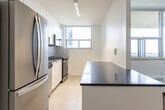Located at 765 Steeles Ave W in North York, Toronto, this one-bedroom, one-bathroom unit offers a well-organized layout across a single floor. Classic parquet wood flooring runs throughout the living, dining, and bedroom areas, adding warmth and character to the bright, white-walled interior.

The open-concept living and dining area is bathed in natural light through large floor-to-ceiling windows, offering expansive city views of the Toronto skyline and surrounding neighbourhood. A baseboard heating unit runs along the window wall, ensuring year-round comfort. The space flows seamlessly into the kitchen, which is separated by a peninsula counter with a dark laminate top — ideal for casual dining or meal prep. The kitchen features white shaker-style cabinetry, stainless steel appliances including a refrigerator and dishwasher, a stainless steel sink, and light tile flooring.

The bedroom is a well-proportioned, quiet retreat with its own large window framing city views and a full-width mirrored sliding closet that enhances the sense of space. The bathroom has been tastefully renovated with white subway tile surrounding the soaker tub and shower, neutral stone-look floor tile, and a clean vanity with storage. The unit also includes a dedicated entryway with dark-panelled doors providing a defined sense of arrival.