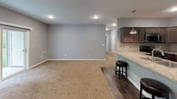 This single-floor residence is thoughtfully designed with a cohesive, modern aesthetic carried throughout. The open-concept living and dining area is anchored by neutral gray walls, recessed lighting, and plush wall-to-wall carpeting, creating a comfortable and versatile space. Sliding glass doors connect the living area directly to a green outdoor space, filling the room with natural light and providing convenient outdoor access.

The kitchen is well-appointed with dark espresso cabinetry, granite countertops, a tile backsplash, and a full suite of stainless steel appliances including a gas range, over-the-range microwave, and refrigerator. A peninsula with seating offers both additional prep space and a casual dining option, with a pendant light overhead adding a refined touch. Wood-look flooring runs through the kitchen and dining area, transitioning to carpet in the living and bedroom spaces.

Multiple bedrooms feature neutral gray walls, plush carpet, and windows overlooking lush greenery, ensuring natural light throughout. The bathroom includes a walk-in shower with white subway tile, a mosaic niche, sliding glass doors, a granite vanity, and wood-look flooring, presenting a clean, modern finish.