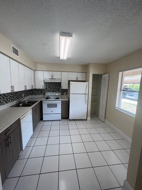 Cocina con encimeras de cuarzo y suelo de baldosas - Cypress Place Apartments
